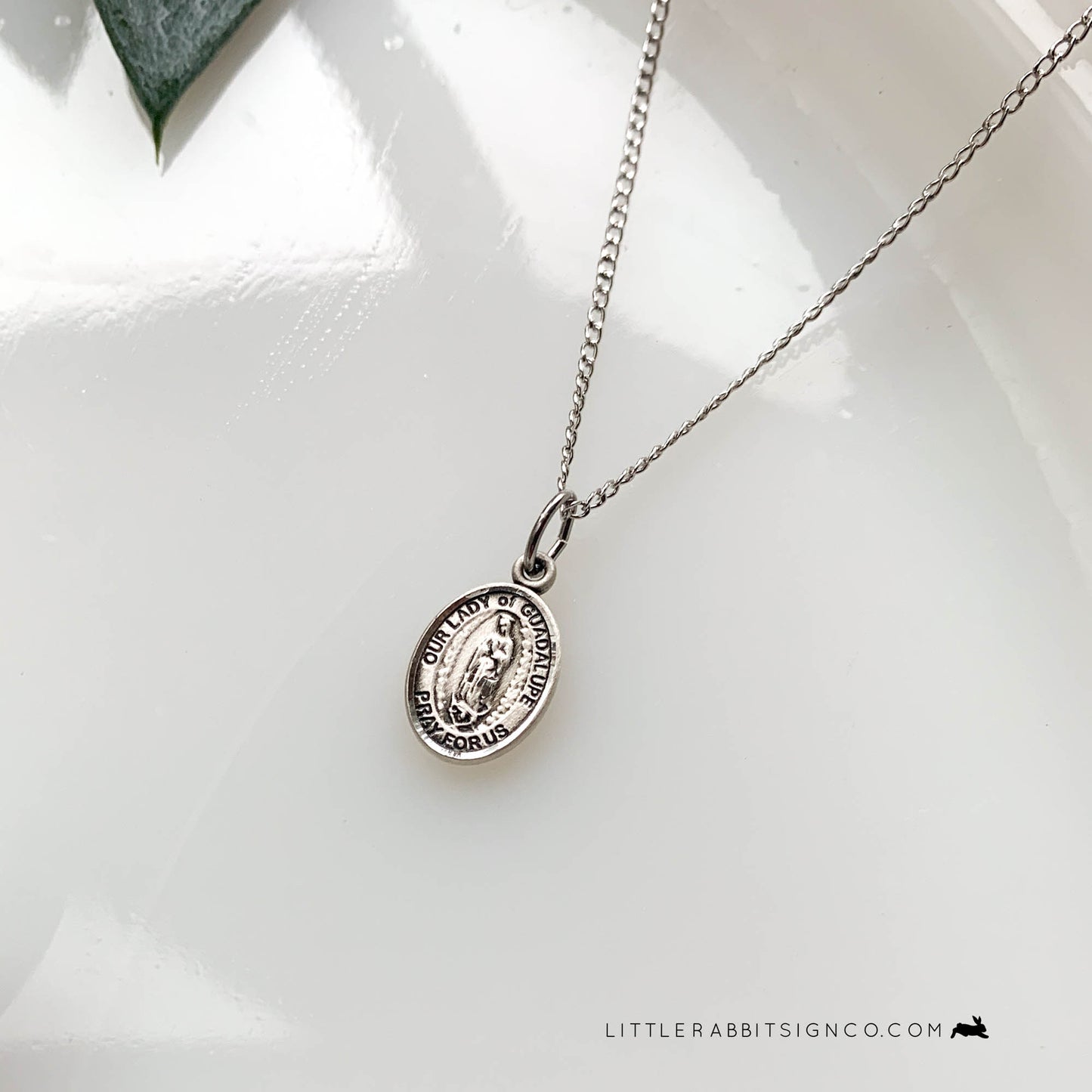 Sterling Silver Our Lady of Guadalupe Necklace on a white background. This gorgeous silver catholic necklace is suspended from a light curb chain. It's the perfect necklace for daily wear if you have a devotion to Our Lady of Guadalupe.