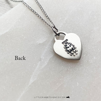 Back of the heart-shaped Miraculous Medal necklace in sterling silver. Shows the traditional Miraculous Medal pendant back.
