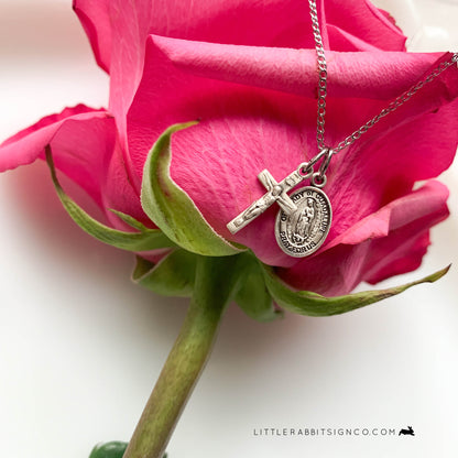 Our Lady of Guadalupe and Crucifix layered minimalist necklace displayed on a beautiful pink rose bud