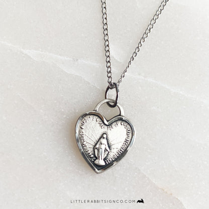 Close up of a heart shaped miraculous medal necklace in sterling silver.